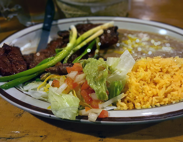 Carne asada with guacamole, rice, and beans.